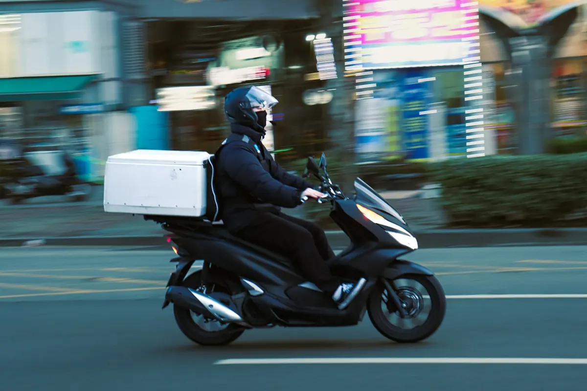 A rider on a motorbike with a delivery box